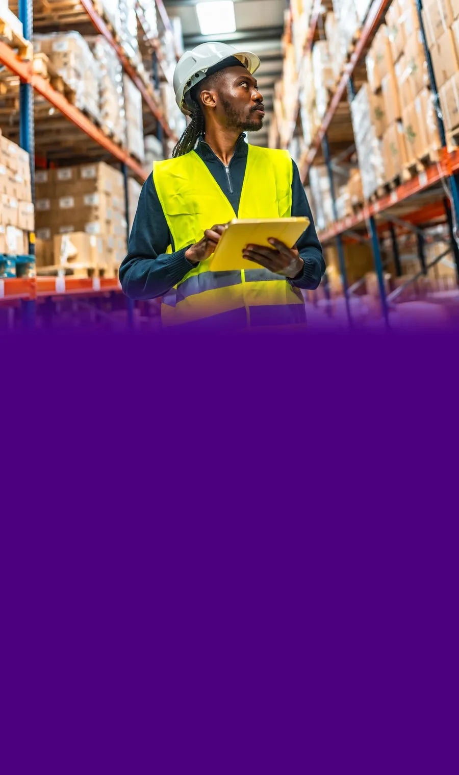 A warehouse associate checking inventory on a tablet in the racks