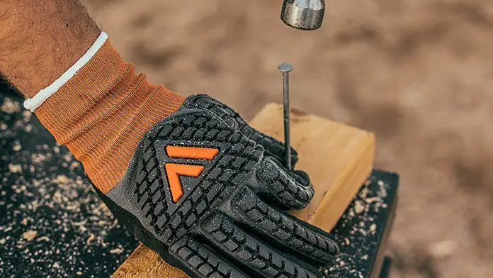 Impact resistant work glove steadying a nail under a hammer