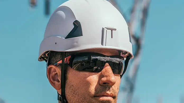 Worker wearing a white safety helmet with chin strap and tinted safety eyewear