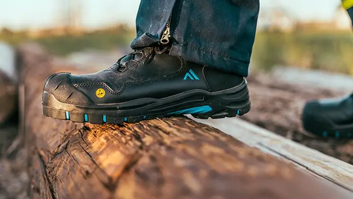 Black safety work boot stepping on a log
